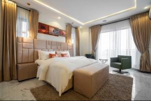 Un dormitorio grande con una cama grande y una silla. en CozyKey Luxury Apartment, en Lekki