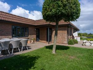 una casa con mesa, sillas y un árbol en Beach Bungalow Sylt 1, en Dikjendeel