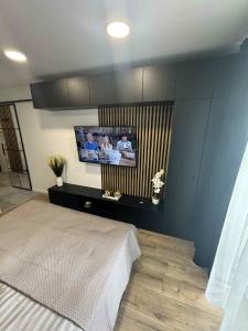a bedroom with a bed and a flat screen tv at Luxury Premium Apartment Tarnów City in Tarnów +2 photos