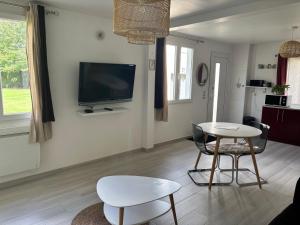 a living room with a table and a tv on the wall at La Petite Lucienne in Saint-Lucien