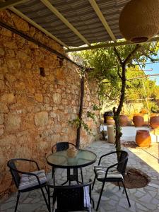 a patio with a table and chairs under a stone wall at Porta Mesta in Chios