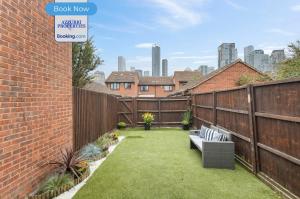 a backyard with a brick fence and a bench at 2BR Flat By Azzurri Properties Short Lets & Serviced Accommodation Canary Wharf With Open Garden, Free Parking & Short Stays in London