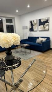 a living room with a blue couch and a glass table at Luxury Apartment 3min To Station in Borehamwood +3 photos