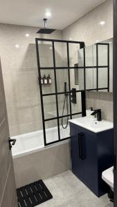 a bathroom with a sink and a bath tub at Luxury Apartment 3min To Station in Borehamwood