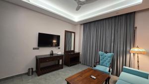a hotel room with a television and a blue chair at Hotel Devaan in Kālānwāli +15 photos