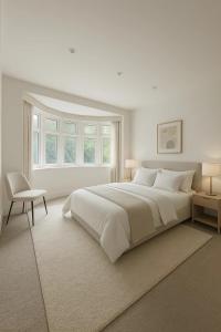 a white bedroom with a large bed and a chair at Modern Luxury 6 Bed Harrow in Hatch End