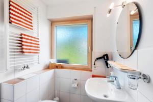 a white bathroom with a sink and a mirror at Gästehaus Hanni in Todtmoos
