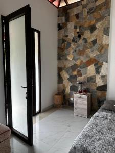 1 dormitorio con puerta y pared de piedra en Geethani's Villa, en Madola