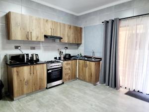 a kitchen with wooden cabinets and a stove at Bole Suites in Lilongwe