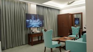 a living room with a tv and a table and chairs at Hotel Devaan in Kālānwāli