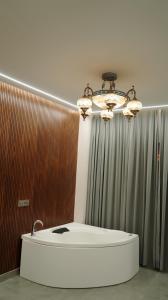 a bathroom with a bath tub and a chandelier at Hotel Devaan in Kālānwāli