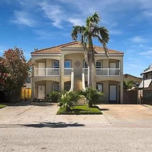 a large house with a palm tree in front of it at Beach & Palms condo condo in South Padre Island