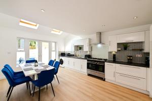 a kitchen with white cabinets and a table and blue chairs at Cosy Mumbles Escape Fun & Relax in The Mumbles