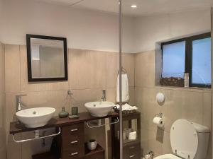 a bathroom with two sinks and a toilet and a mirror at 500m from Rosebank Mall - Cottage on Bath in Johannesburg +18 photos