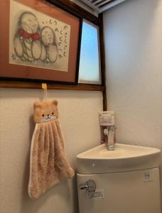 ein Badezimmer mit Toilette und einem Handtuch an der Wand in der Unterkunft Yui HOSTEL in Tokio + 16 Fotos