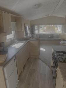 a small kitchen with white cabinets and a stove at 6 Berth Caravan With Decking In Hunstanton At Manor Park Holiday Park Ref 23062T in Hunstanton