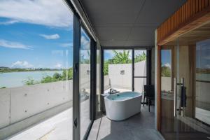 宮古島にあるVilla M BAYFRONT YONAHA -Pool&Sauna Retreat-の浴槽があり、水辺の景色が見えるバスルーム
