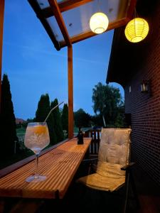 a glass of wine sitting on a wooden table on a patio at Knut's Nest in Westoverledingen