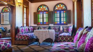 a room with a table and chairs and stained glass windows at Riad El Ouedghiri in Fez