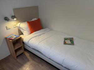 a small bed with an orange pillow and a night stand at Estivo mobile homes on Camping Bella Italia in Peschiera del Garda