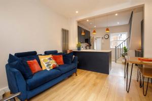 ein Wohnzimmer mit einer blauen Couch und einer Küche in der Unterkunft Lockwood Cottage, Close to Monk Bar, sleeps 4 in York