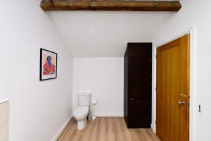 a bathroom with a toilet and a wooden door at Cosy Mumbles Escape Fun & Relax in The Mumbles +27 photos