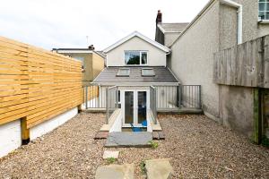 a backyard with a house and a wooden fence at Cosy Mumbles Escape Fun & Relax in The Mumbles