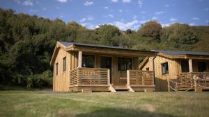a wooden cabin with a large porch and a porch at Glen Wyllin Campsite in Kirkmichael