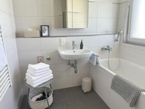 a white bathroom with a sink and a bath tub at "VERWEILZEIT" - Premium Apartments Seekirchen in Seekirchen am Wallersee