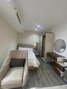a bedroom with a bed and a couch and a mirror at Luxury Studio Zed Park Compound Sheikh Zayed in Sheikh Zayed