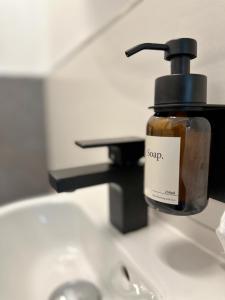 a bottle of soap sitting on top of a sink at "VERWEILZEIT" - Premium Apartments Seekirchen in Seekirchen am Wallersee