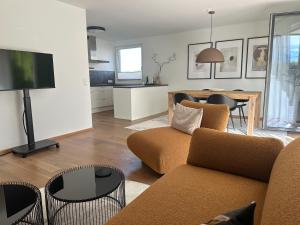 a living room with a couch and a tv and a table at "VERWEILZEIT" - Premium Apartments Seekirchen in Seekirchen am Wallersee
