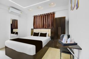 a bedroom with a white bed and a desk and a bed sidx sidx at Townhouse Sapphire Star Chappan Market in Indore