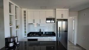 Una cocina con gabinetes blancos y un refrigerador de acero inoxidable. en Krone Apartments Barra Velha, en Barra Velha