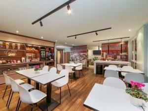 a restaurant with white tables and white chairs at B&B Hotel Berlin-Dreilinden in Kleinmachnow
