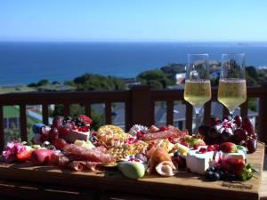 un plato de comida y dos copas de vino en Waves & Whales, en Brenton-on-Sea