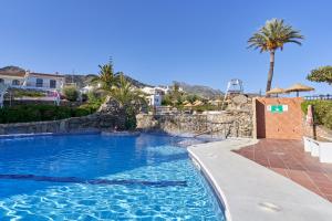 una piscina en un complejo con palmeras en Casa Mimosa Capistrano Nerja, en Nerja