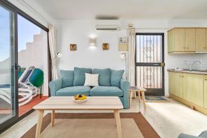 Una sala de estar con un sofá azul y una mesa. en Casa Mimosa Capistrano Nerja, en Nerja