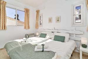 2 camas en una habitación blanca con ventanas en Casa Mimosa Capistrano Nerja, en Nerja 22 fotos más