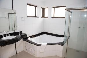 un baño con bañera y lavabo en Hotel Ouro Lavras, en Lavras