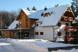 ein Haus mit Schnee auf dem Boden neben einer Straße in der Unterkunft Bolfenk B6 in Hočko Pohorje