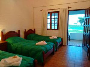 Una sala de estar con dos camas verdes y un balcón. en Hostal Naico, en Naicó 18 fotos más
