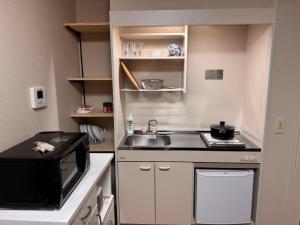 a small kitchen with a sink and a microwave at Cozy House Namba in Osaka