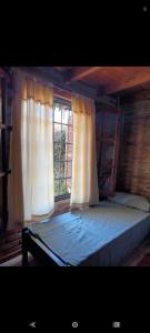 a bedroom with a bed with curtains and a window at Pao Pei in Santa Rosa de Calamuchita