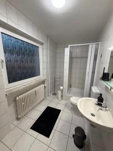 a white bathroom with a sink and a window at Immo-Vision - Modern Living Apartments, Zentral, Parkplatz, Küche, Wlan in Wolfsburg +49 photos