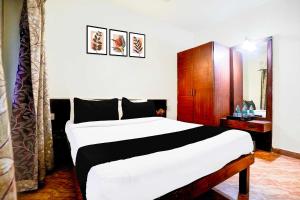 a bedroom with a large bed and a wooden cabinet at Hotel O Holiday Street Calangute formerly Shruti Resort in Goa +17 photos
