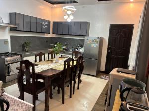 a kitchen with a table and chairs and a refrigerator at Spacious 3BR Home Comfy Beds Great Location in Kaganjuan