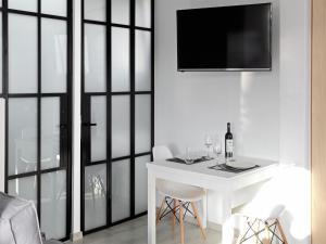 雅典的住宿－雅典景閣樓公寓- 02，一张带椅子的白色桌子和墙上的电视