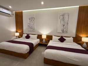 two beds in a hotel room with drawings on the wall at Four Chalets Yala in Tissamaharama +40 photos