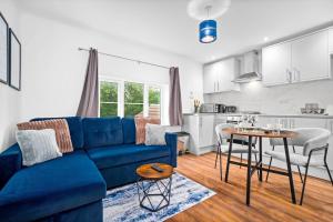 a living room with a blue couch and a kitchen at Comfortable 2 Bed Apt, Sleeps 8, Parking, Great for Contractors, Families and Leisure Stays, West Midlands, near Birmingham, Edenwood Residence in Droitwich